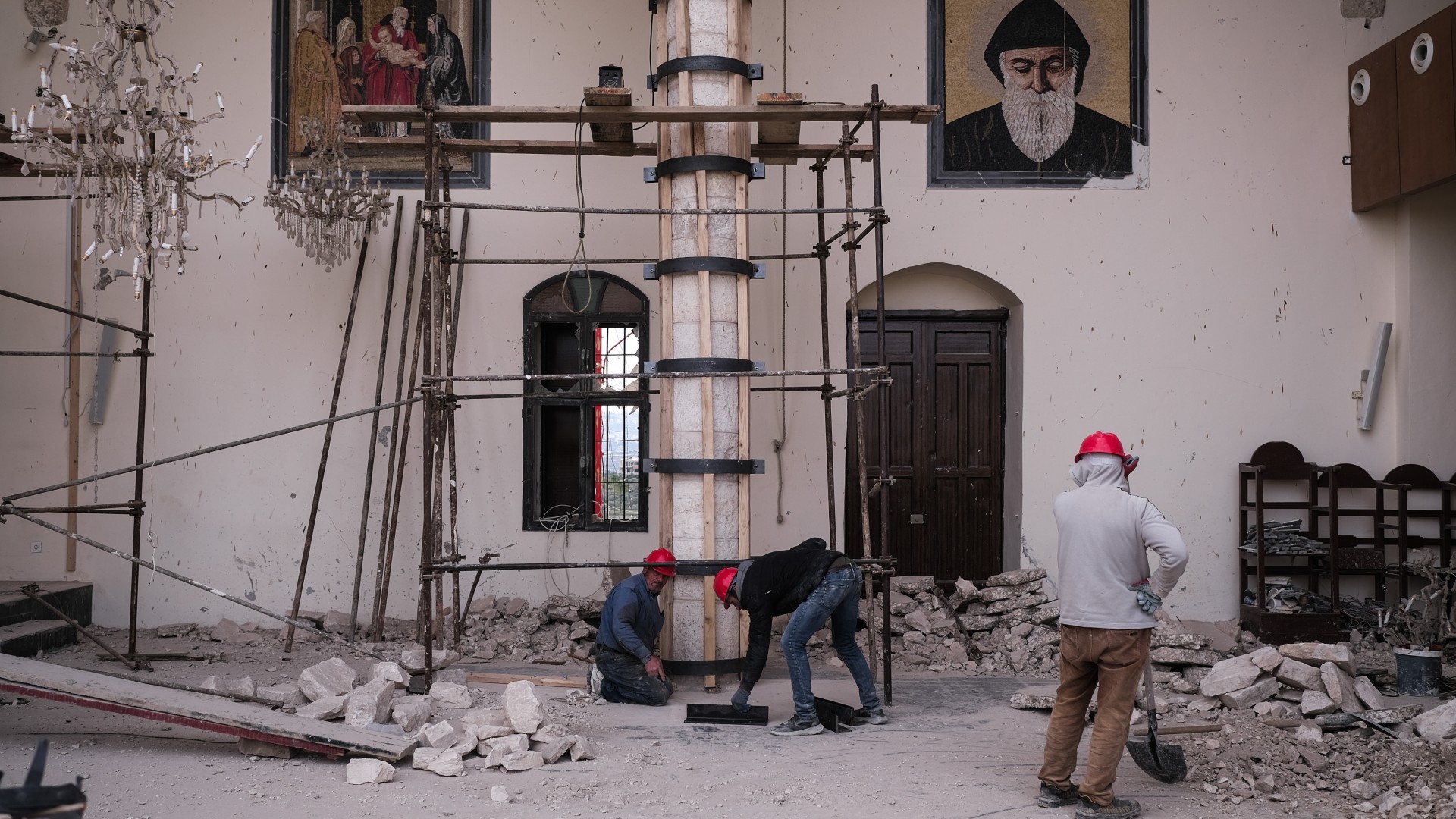 Workers repair a church in Derdghaya that was badly damaged by an Israeli strike, 21 December (João Sousa/MEE)