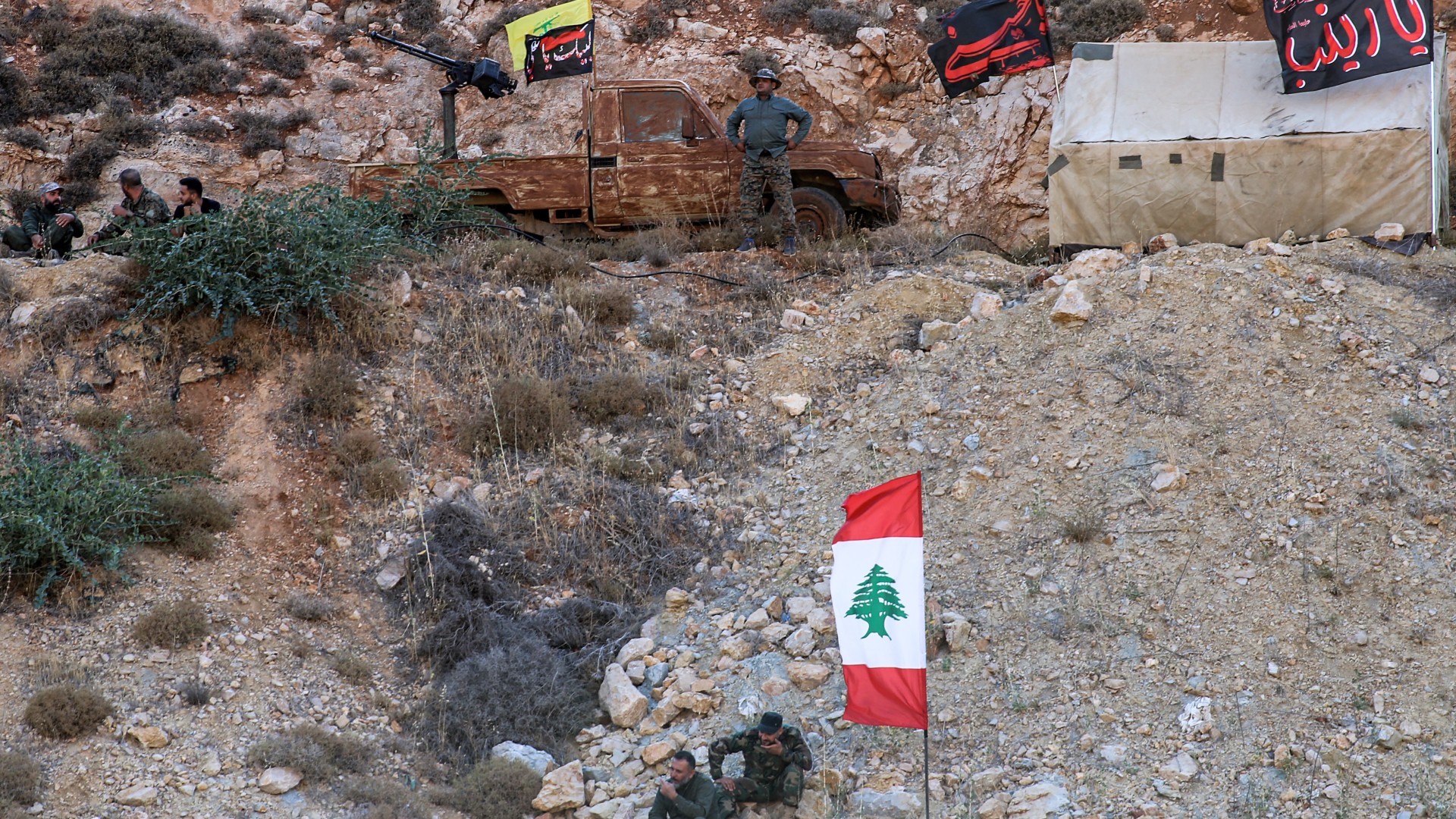 Members of Hezbollah pose with their group's flags at a camp in the Janta region in the east of the country on 19 August, 2022 (AFP)