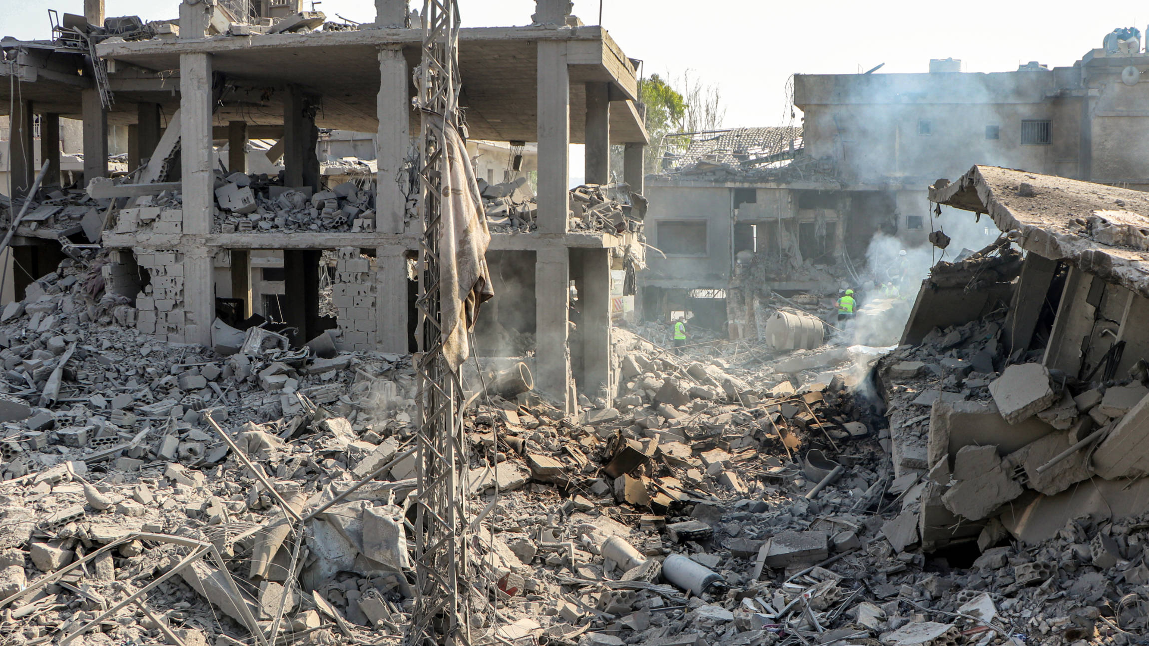 Civil defence members search for survivors through the rubble of a destroyed building at the site of an Israeli air strike on the village of Qana in southern Lebanon on 16 October 2024 (AFP)