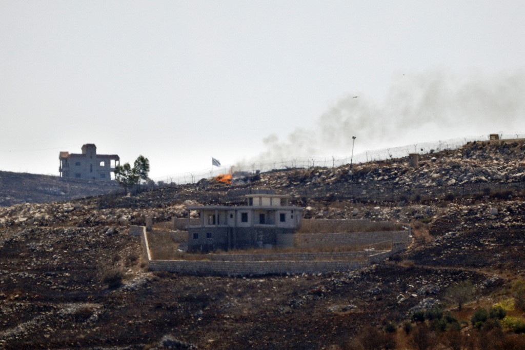 A photograph taken from the southern Lebanese village of Chaqra shows an Israeli flag fluttering over the burnt fields of the border village of Mais al-Jabal, burnt during Israeli military operations on August 11, 2026. 