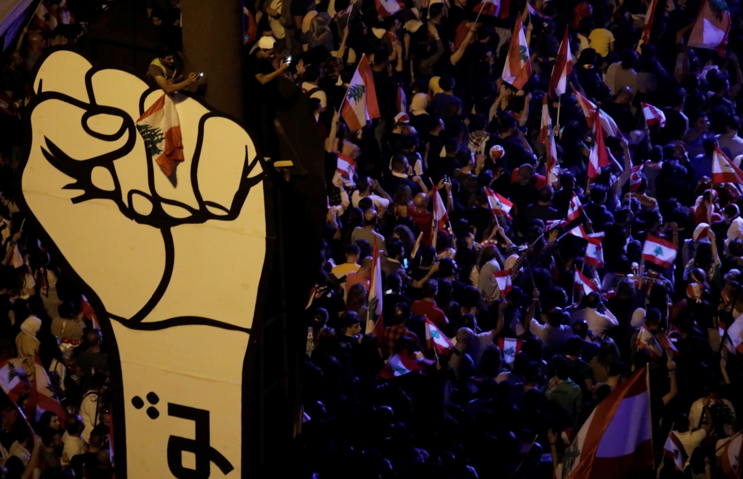Demonstrators hold Lebanese flags as they gather at Martyrs' Square in Downtown Beirut on 3 November 2019 (Reuters)