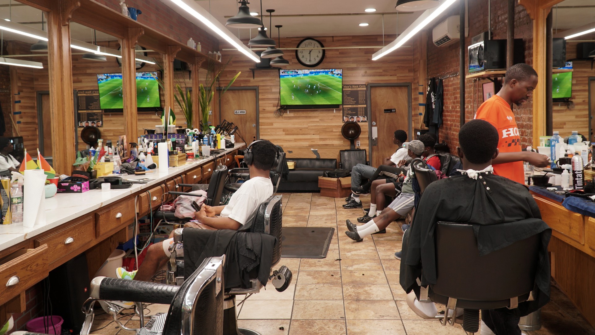 Fans watch World Cup fixtures as they await a haircut in a barber shop in Little Senegal  (MEE/Azad Essa)