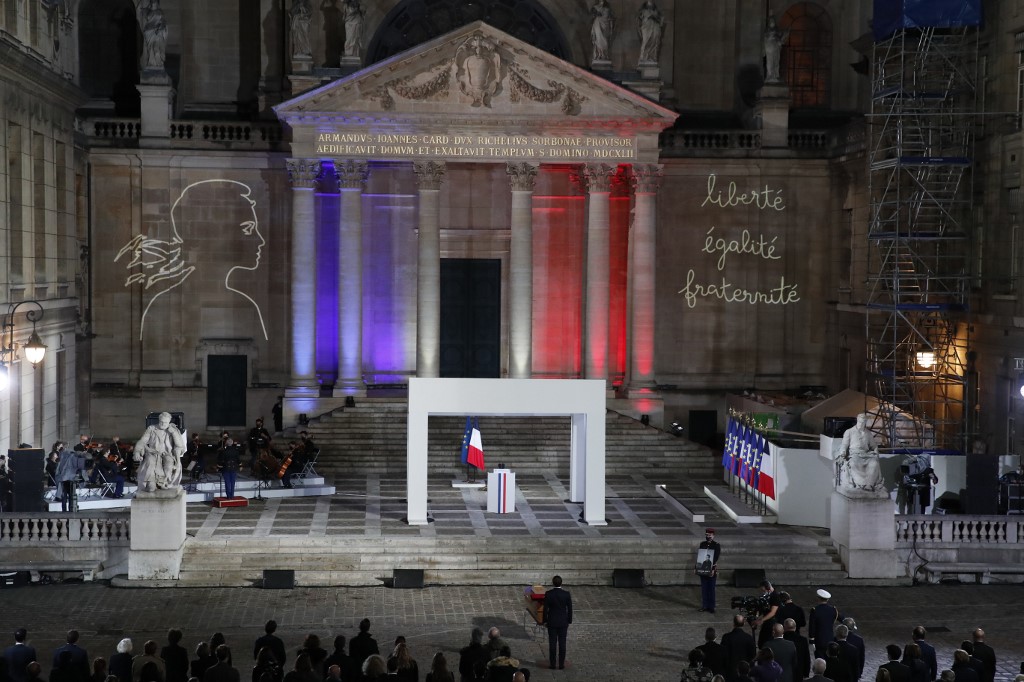 French President Emmanuel Macron, centre, pays his respects in front of Paty’s coffin in Paris on 21 October (AFP)