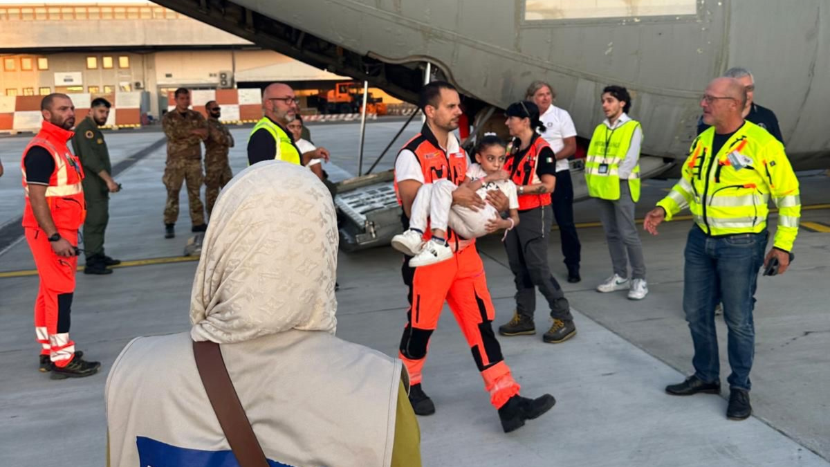 A man carries a Palestinian child getting evacuated from Egypt to Italy to receive medical treatment on 9 August 2024 (PCRF)