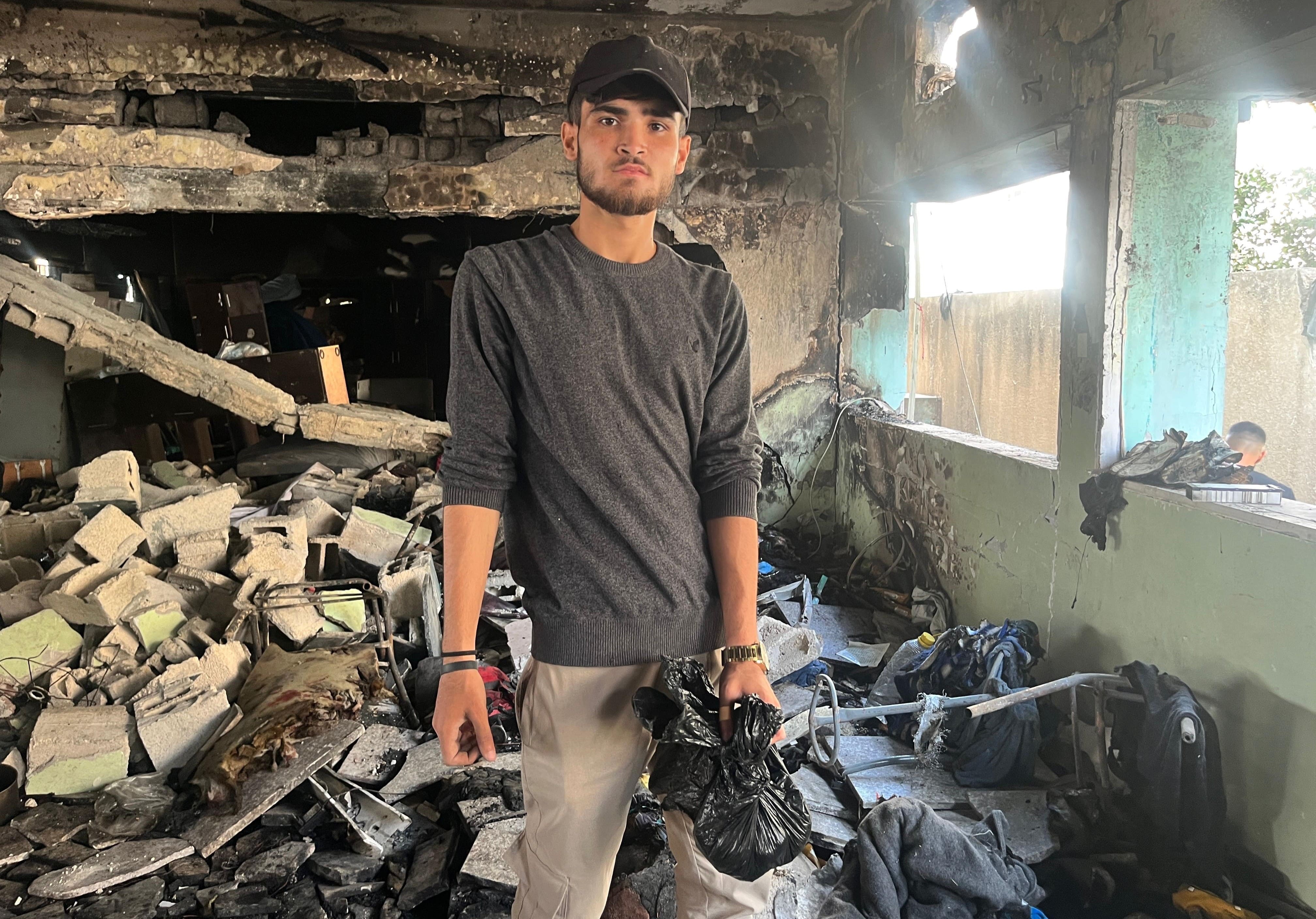 Mohammad Shaker al-Masri, 21 years-old, pictured holding a black bag containing the remains of victims following an Israeli attack on a school-turned-shelter in Gaza City (MEE/Maha Hussaini)