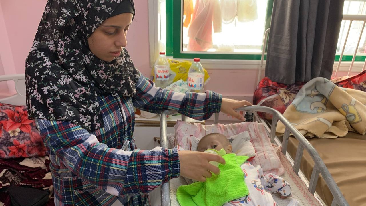 Najwa Aram leans over the crib where her five month-old Suwar Ashour, who weighs less than three kilograms, is laying down (MEE/Ahmed Aziz)