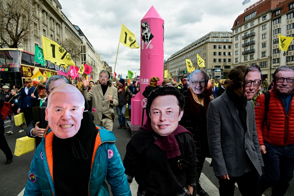 Climate activists of Extinction Rebellion wearing masks of company CEOs including Twitter's Elon Musk and Bill Gates take part in a demonstration in Berlin on April 13, 2023.