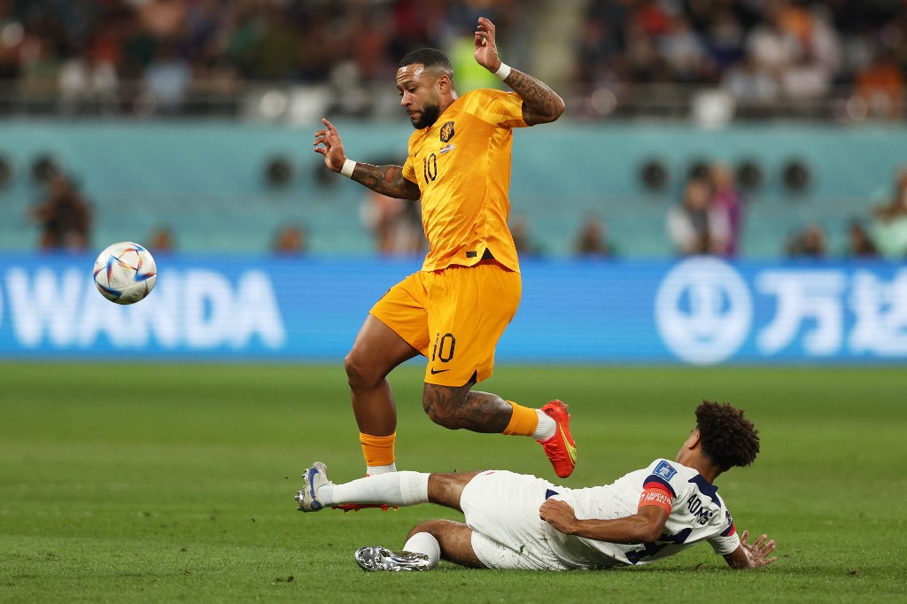 Netherlands forward Memphis Depay fights for the ball with US midfielder Tyler Adams during the World Cup in Qatar on 3 December 2022 (AFP)
