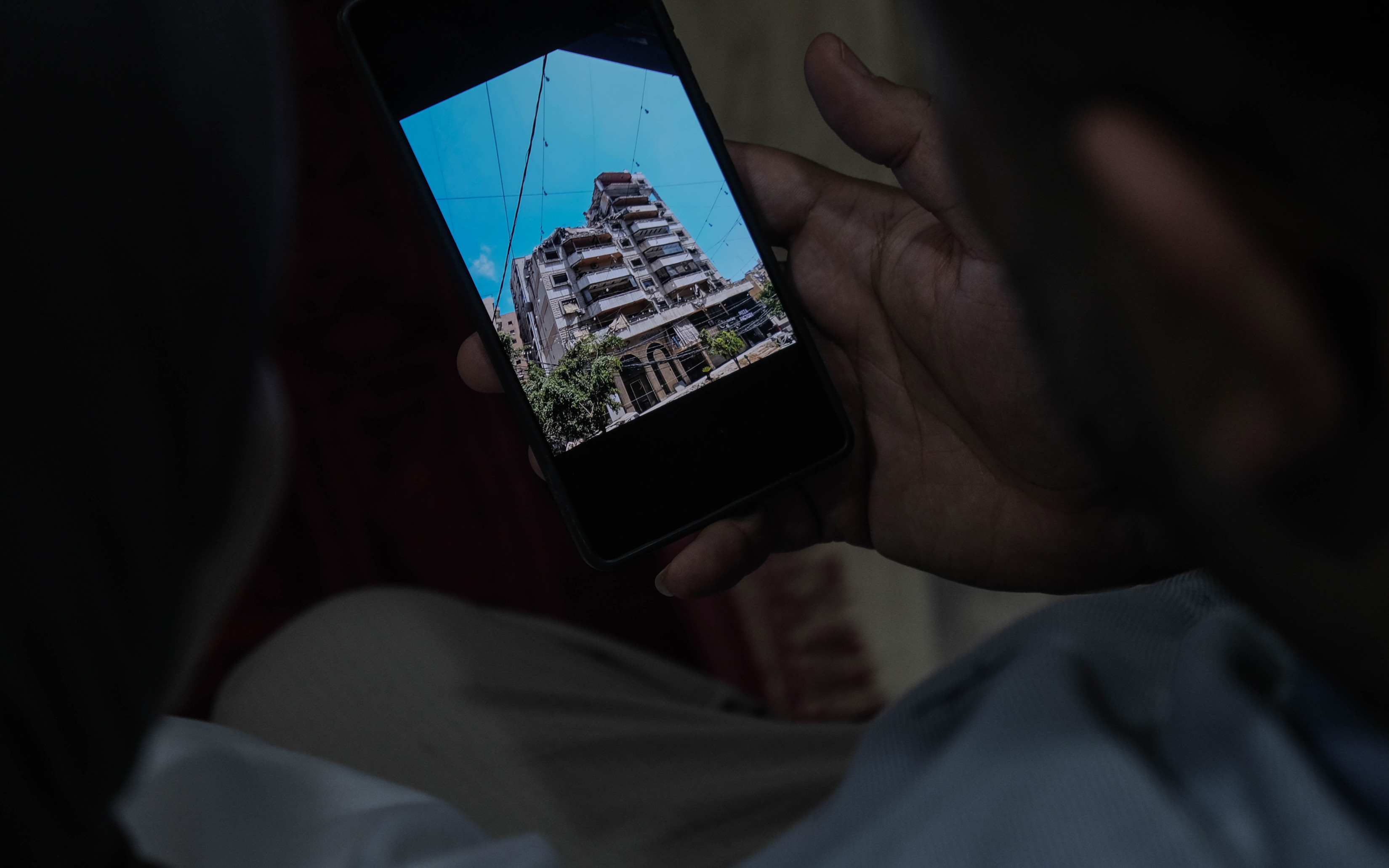 Nour and Mohammad look at a photo of their building after it got struck by an Israeli missile in Dahyeh, Beirut (Zaynab Mayladan/MEE)
