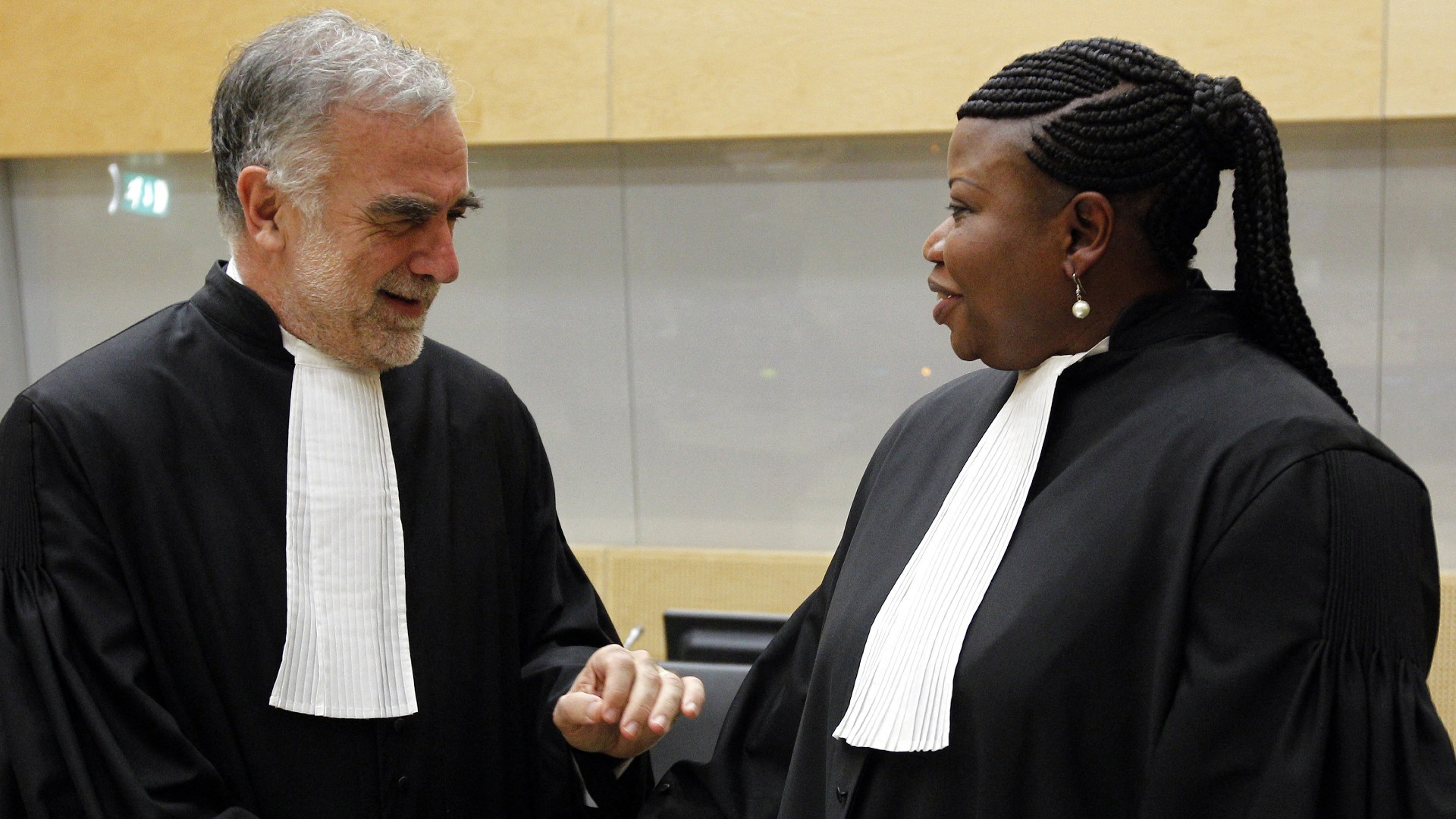 Former ICC chief prosecutor Luis Moreno-Ocampo (L) speaks with then ICC's new chief Fatou Bensouda (R) after her swearing-in ceremony, 15 June 2012 (File photo/AFP)