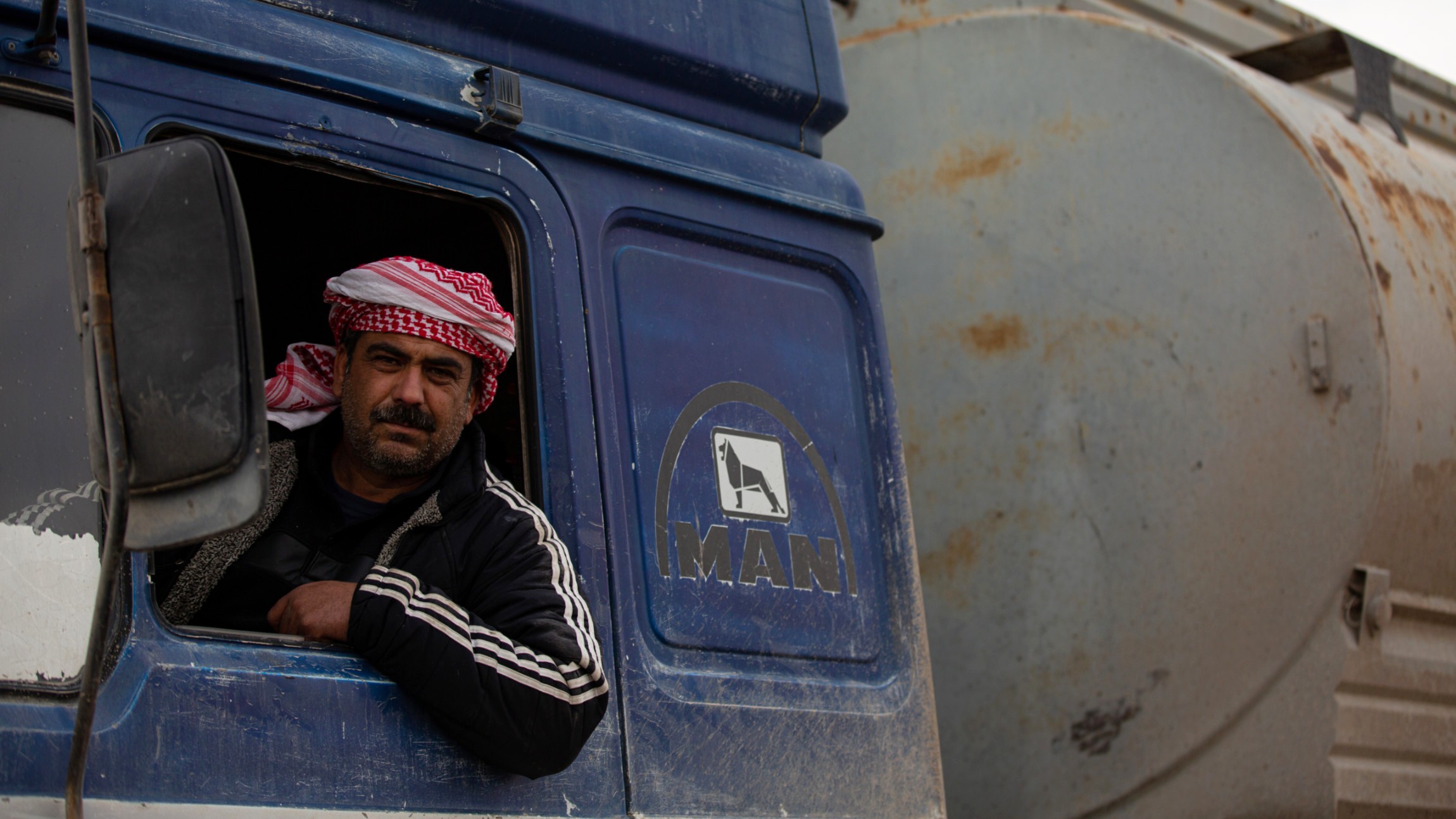 A truck driver waits at the Omar oil field for his vehicle to be loaded before transporting crude oil to a refinery, 23 January 2026 (Hosam Katan/MEE)