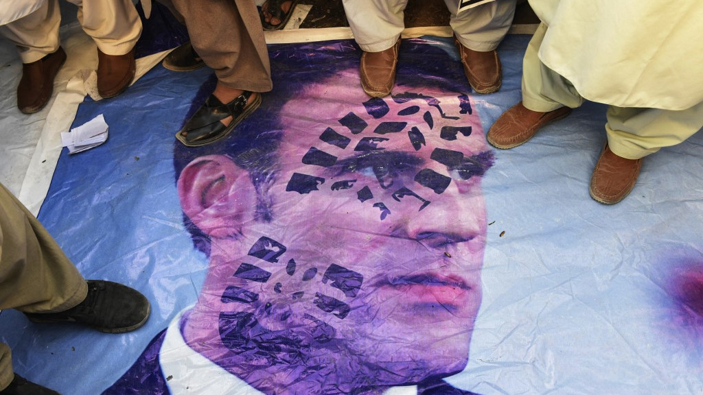 Muslim demonstrators stand over a poster of French President Emmanuel Macron in Quetta, Pakistan, in October 2020 (AFP)