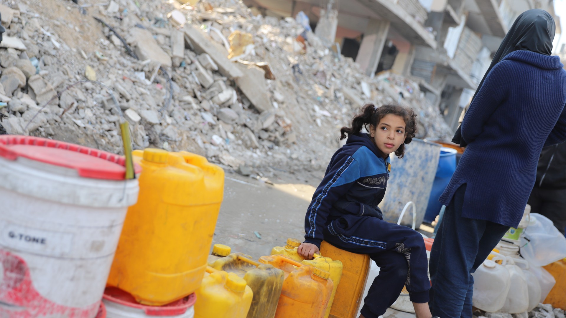 A Palestinian child waits to fill up her jerry can in one of the few places in Gaza City where water is available (Mohammed al-Hajjar/MEE)