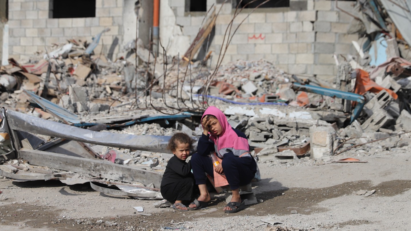 Palestinian children sit near the rubble of their destroyed home in Gaza City on 2 February 2025 (Mohammed al-Hajjar/MEE)