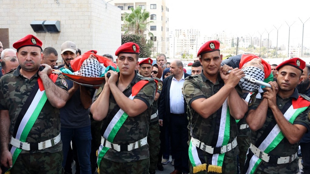 Palestinian security officers carry the bodies of Ibrahim Wadi, 62-years-old, and his son Ahmad Wadi, 25-years-old, two of four Palestinians killed by Jewish settlers the day before, during their funeral in the West Bank city of Nablus on October 12, 2023.