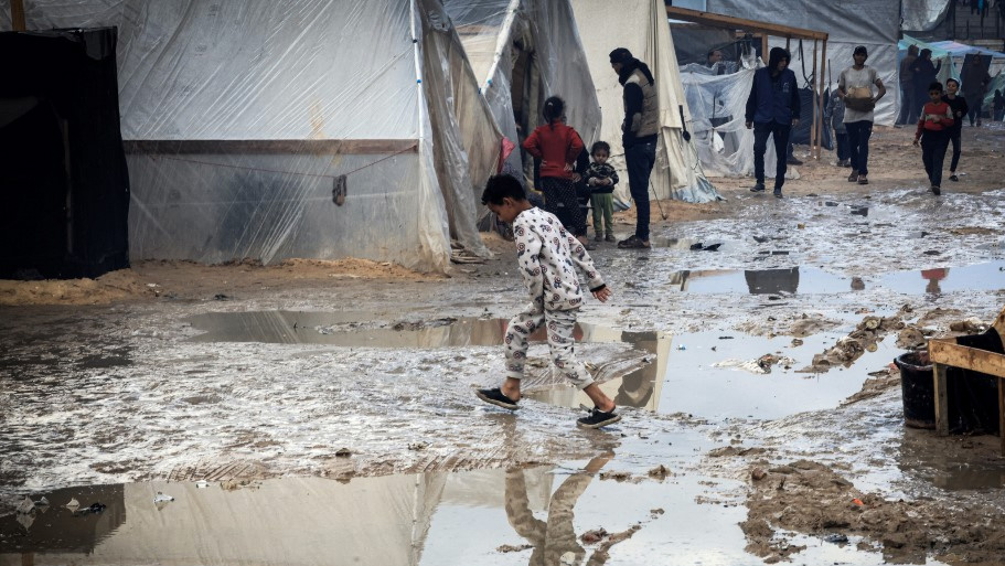 A Palestinian child walks past tents at a makeshift camp housing displaced Palestinians, in Rafah in the southern Gaza Strip, on 2 January 2024 (AFP)