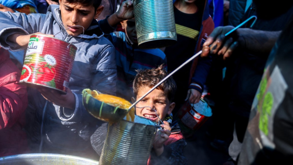 Displaced Palestinians receive food at a distribution centre in Deir al-Balah, Gaza, on 26 November 2024 (Bashar Taleb/AFP)