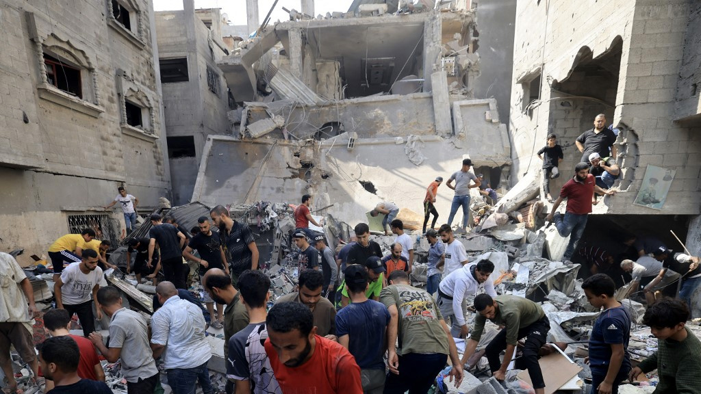 Palestinians look for survivors amid the rubble of a building hit in an Israeli air strike in the southern Gaza Strip on 24 October 2023 (AFP)