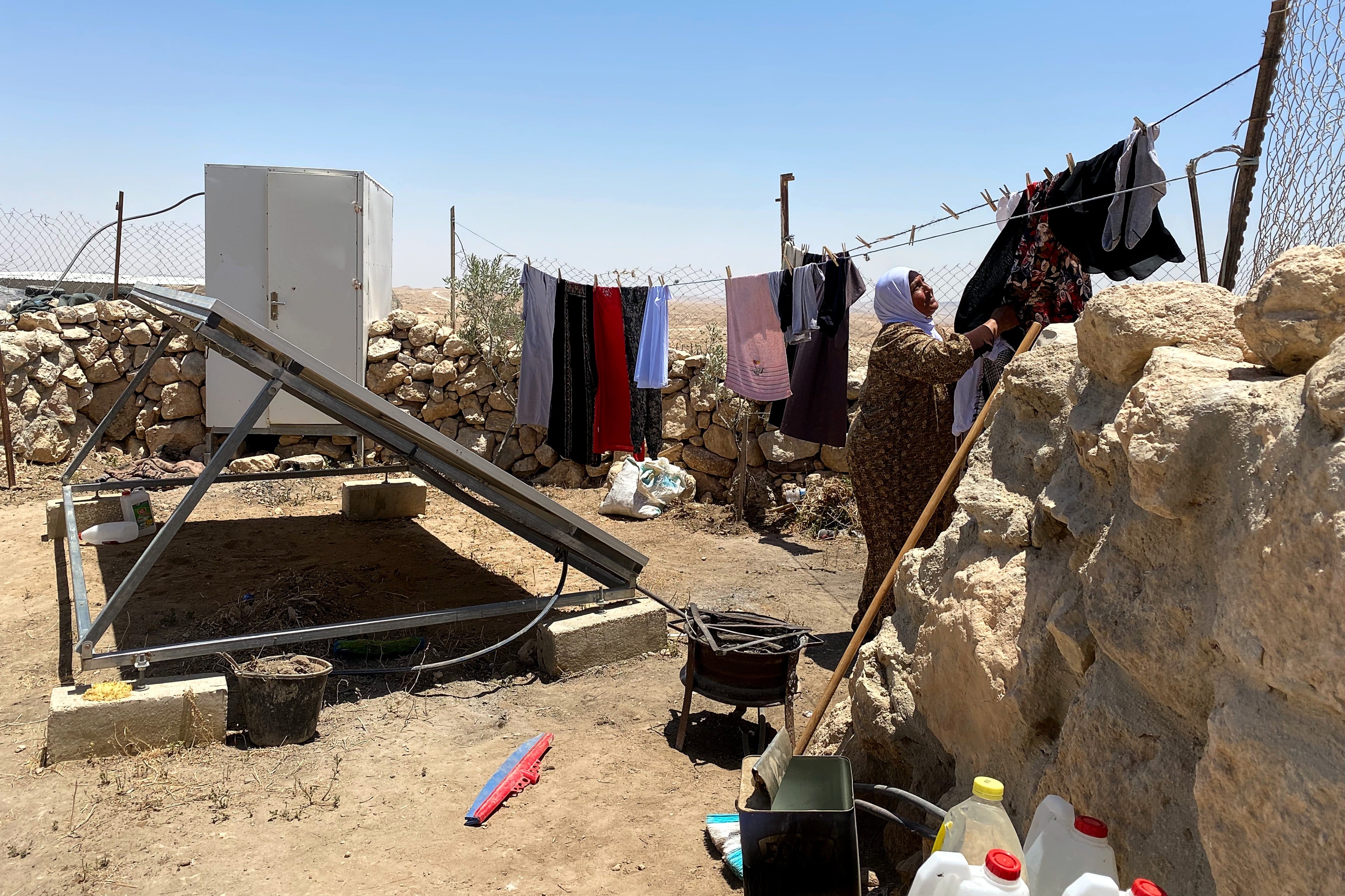 A Palestinian woman hangs clothes outside her home in village on 19 June 2022. (MEE/Shatha Hammad)