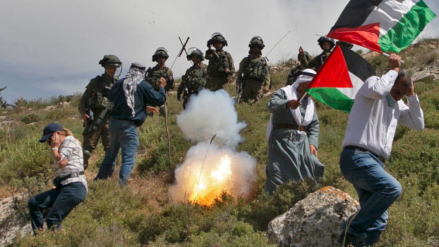 Palestinian protesters run from tear gas fired by Israeli forces during a demonstration against the establishment of Israeli outposts on Palestinian land, in Beit Dajan, occupied West Bank, in April 2021 (AFP)