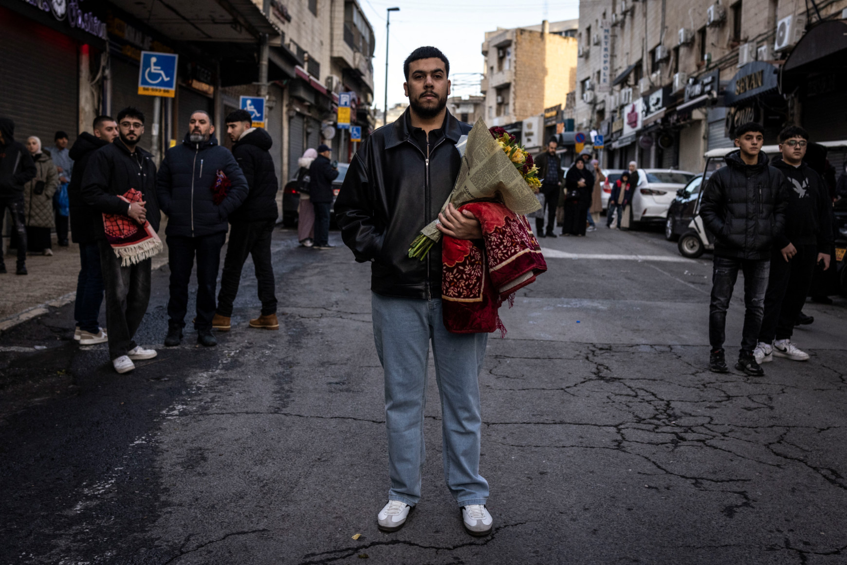 A Palestinian worshipper holds a bouquet of flowers and a prayer mat after early morning prayers for Eid al-Fitr along Salah al-Din street in Jerusalem, 20 March 2026 (John Wessels/AFP)