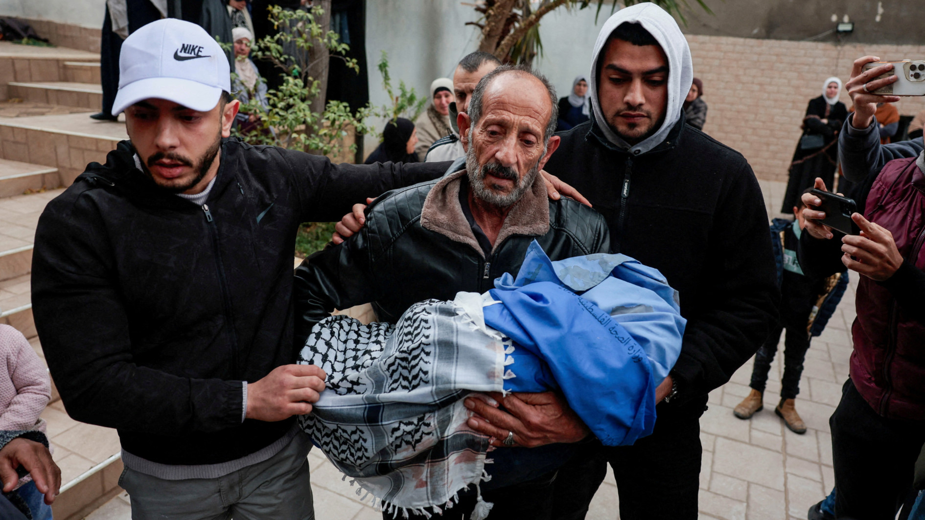 A mourner carries the body of a Palestinian child who was killed with his parents and sibling when Israeli forces opened fire at their car in Tammoun, West Bank, 15 March 2026 (Reuters)