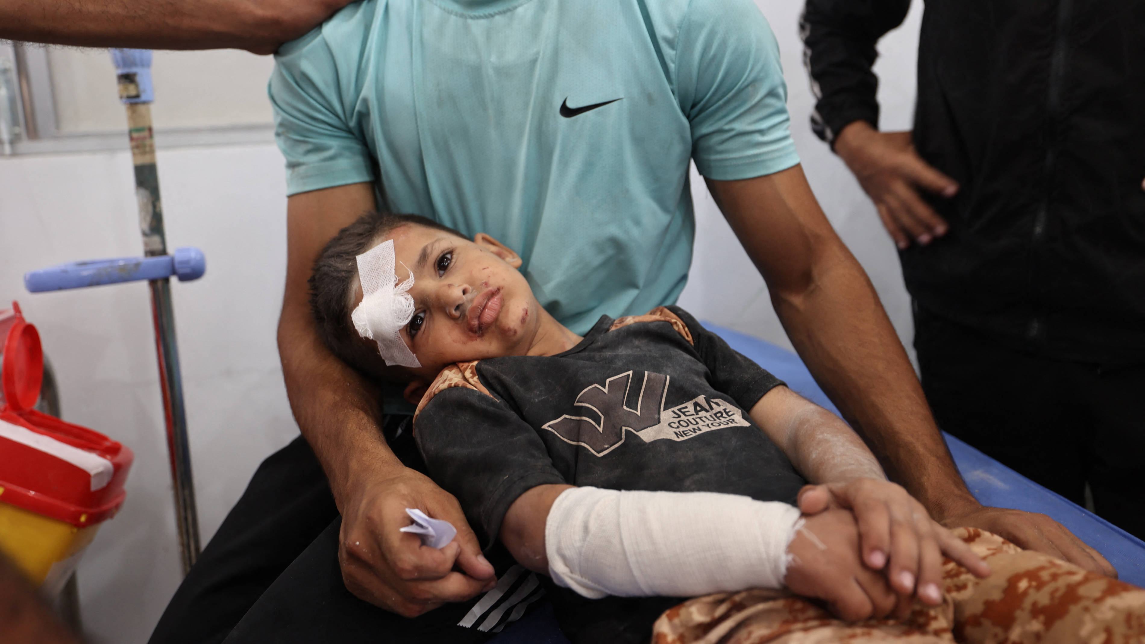A man comforts a wounded child after receiving treatment at Al-Awda Hospital at the Nuseirat refugee camp in the central Gaza Strip, 19 May 2025 (AFP)