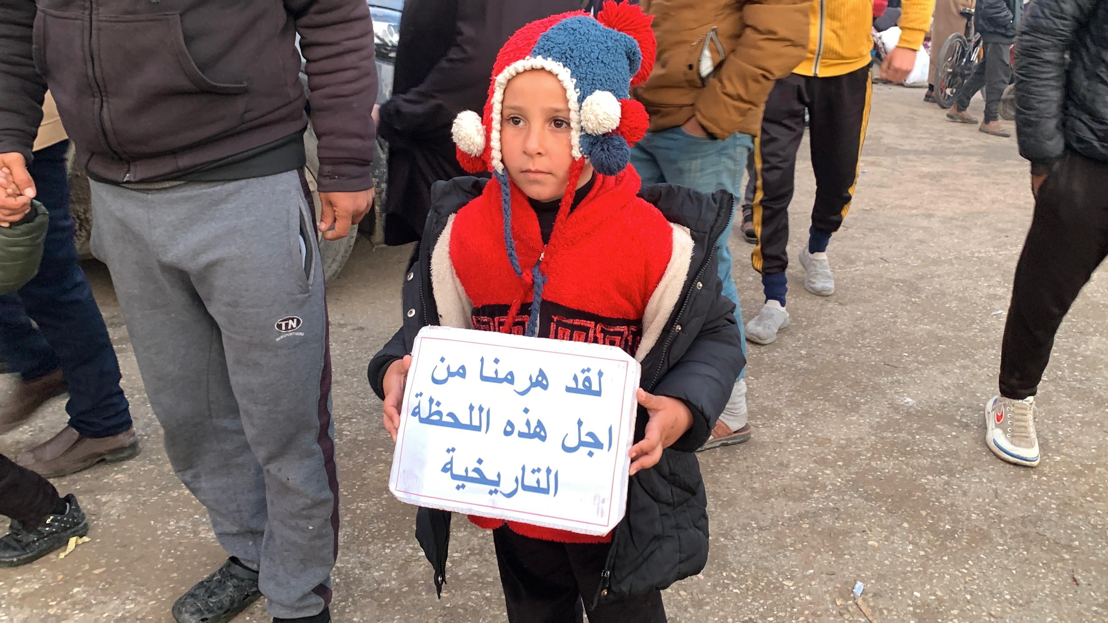 A Palestinian girl returning to north Gaza holds a sign that reads: 