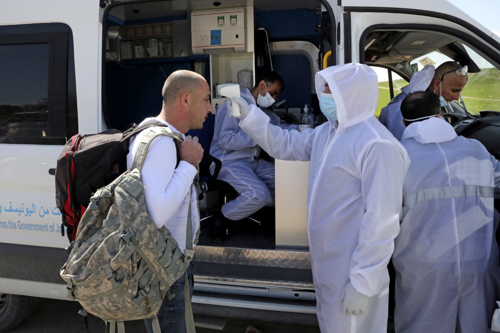 A Palestinian worker gets his temperature checked at the Mitar checkpoint in the occupied West Bank on 25 March (AFP)