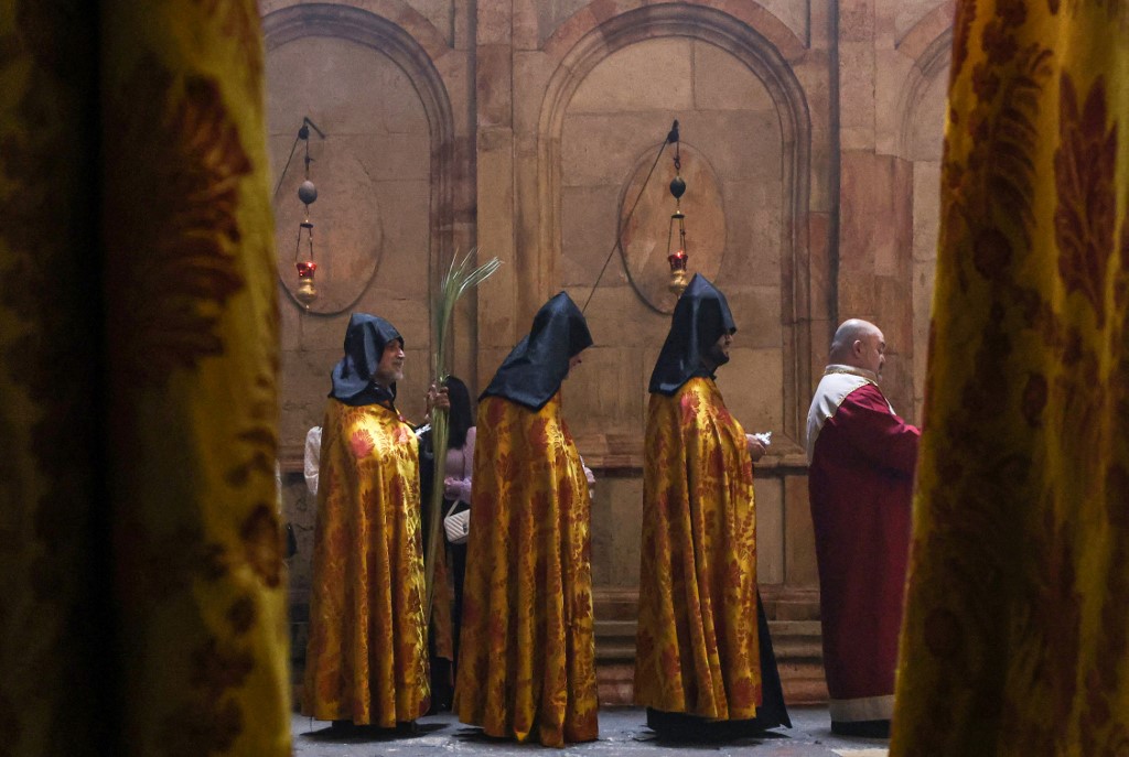 Des prêtres en procession autour de l’édicule, endroit où Jésus-Christ aurait été enterré, lors du dimanche des Rameaux à l’église du Saint-Sépulcre à Jérusalem (AFP)