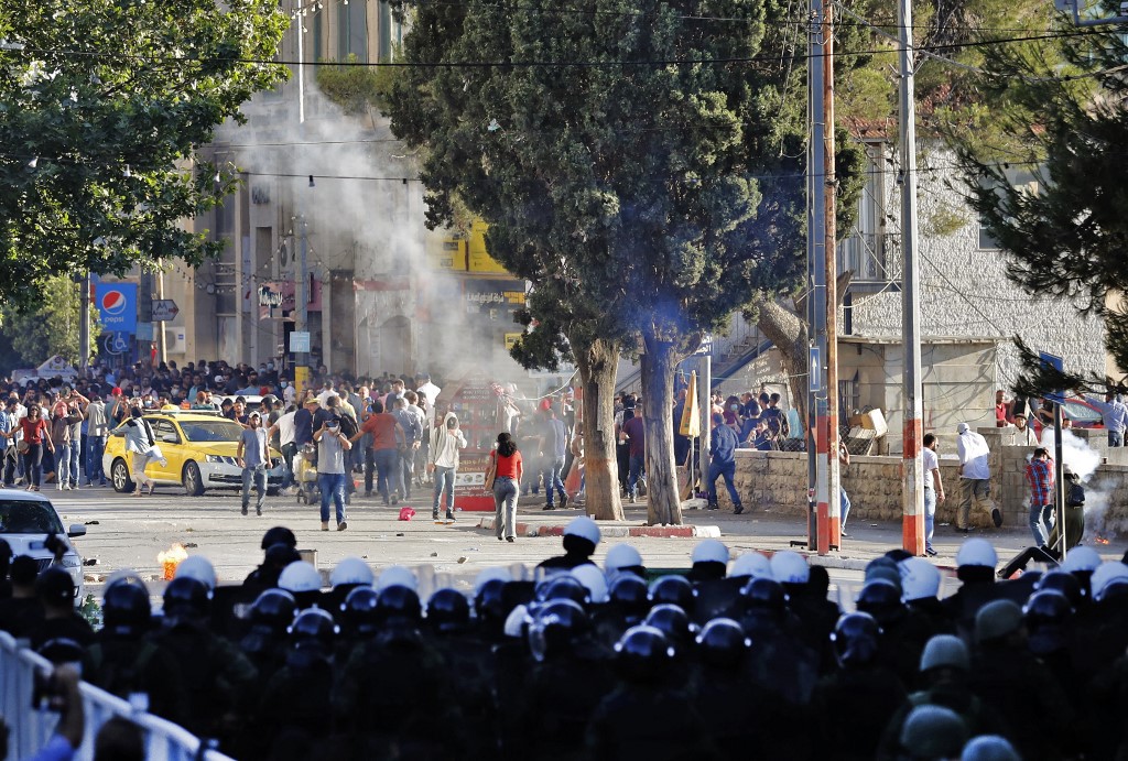 Palestinian protesters and security forces gather in Ramallah on 26 June 2021 (AFP)