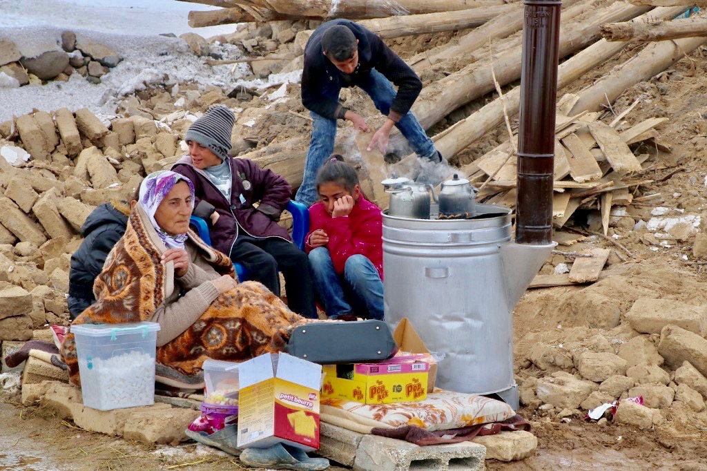 People gather around stove in Baskale, in Turkey's Van province, after earthquake on Sunday (AFP)
