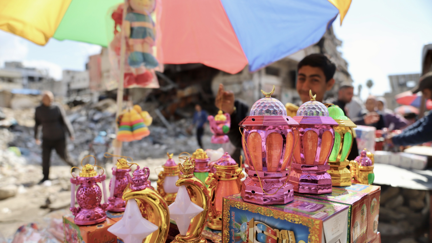 A Palestinian boy sell lanterns and toys on a stand amid a destroyed neighbourhood in northern Gaza on 11 March 2024 (Mohammed al-Hajjar/MEE)