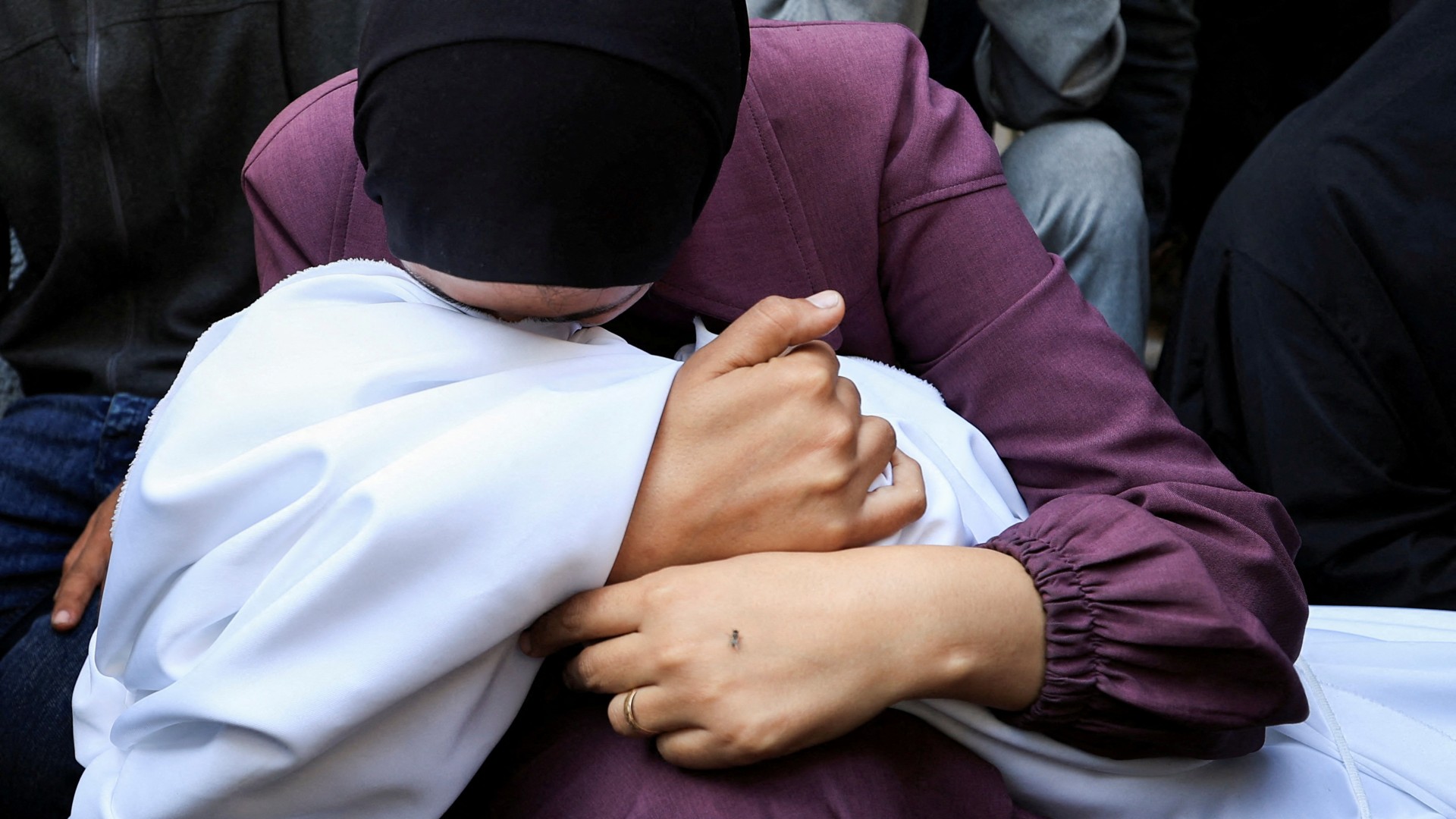 A woman holds the body of a Palestinian who was killed, according to medics, in Israeli strikes, as mourners gather during the funeral at Al-Shifa hospital, in Gaza City, June 4, 2025. REUTERS/Dawoud Abu Alkas TPX IMAGES OF THE DAY