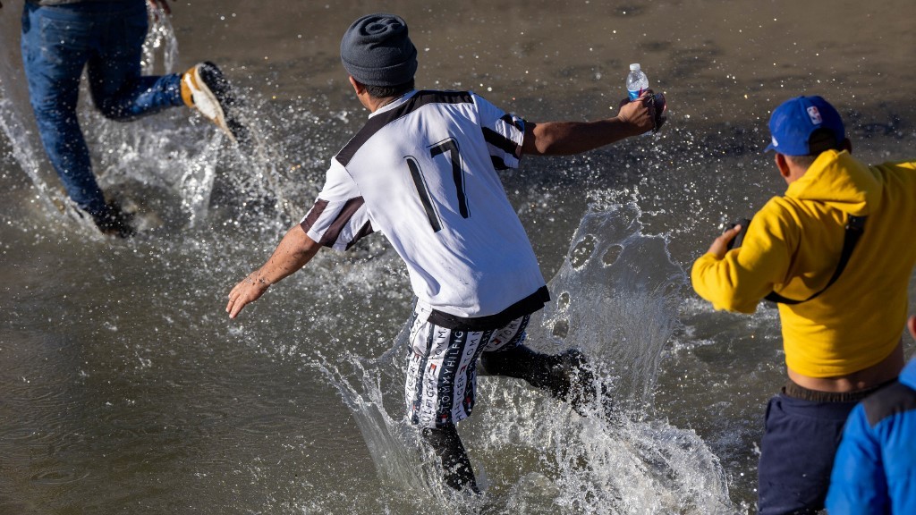 People run to cross the Rio Grande into the US state of Texas from Mexico on 8 January 2023 (AFP)