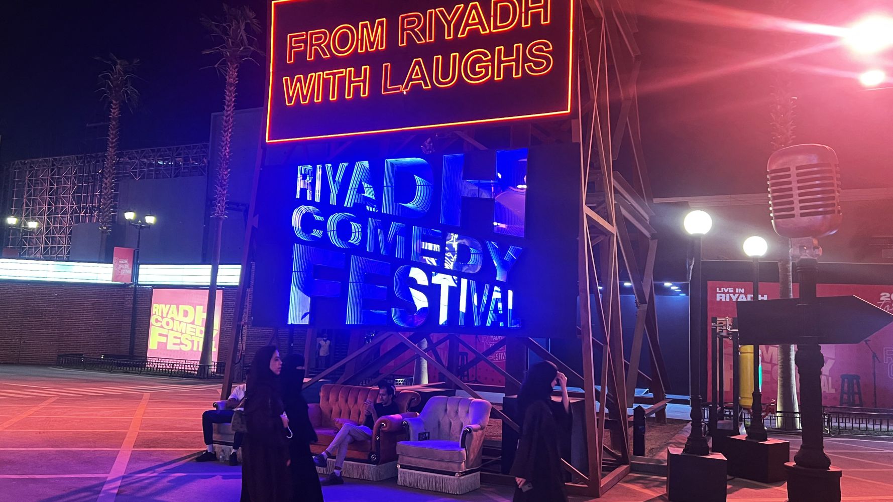 People walk past an installation showcasing the Riyadh Comedy Festival at Boulevard City in the Hittin neighbourhood of Riyadh on October 6, 2025. Jokes about geriatric sex and endless profanity have been embraced by Saudi fans at the Riyadh Comedy Festival even as foreign comedians face a backlash for taking part. The star-studded event, backed by a Saudi government body, has driven a wedge through the stand-up scene, as comics who staunchly defend free speech in the West are accused of hypocrisy. Fayez Nu