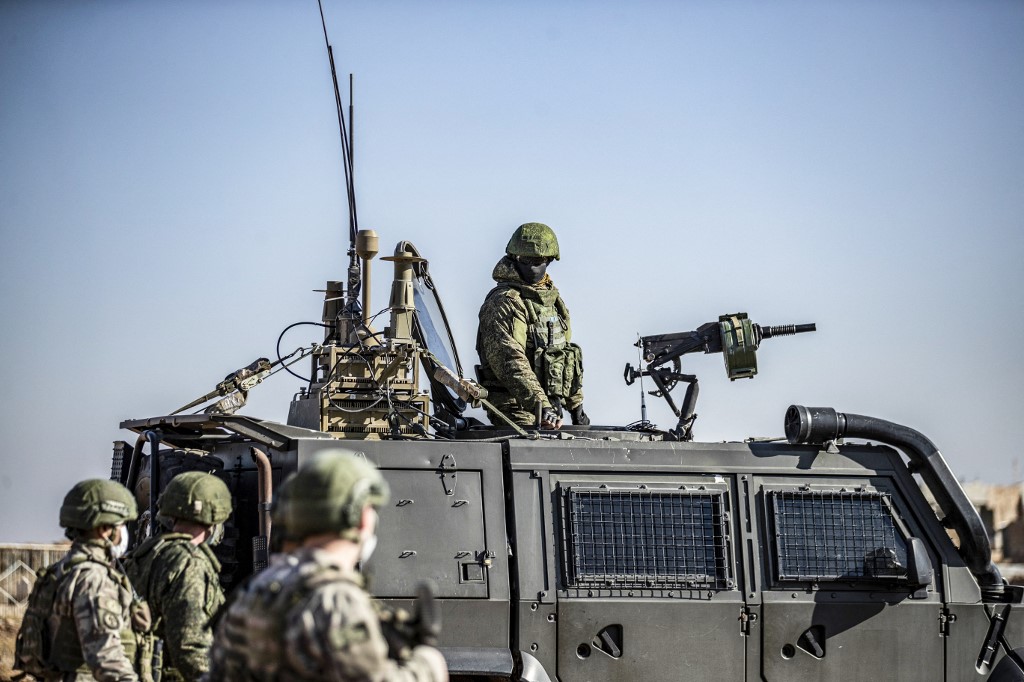 A Russian soldier looks on as Turkish soldiers walk by during a joint patrol in Hasakah province in December 2020 (AFP)