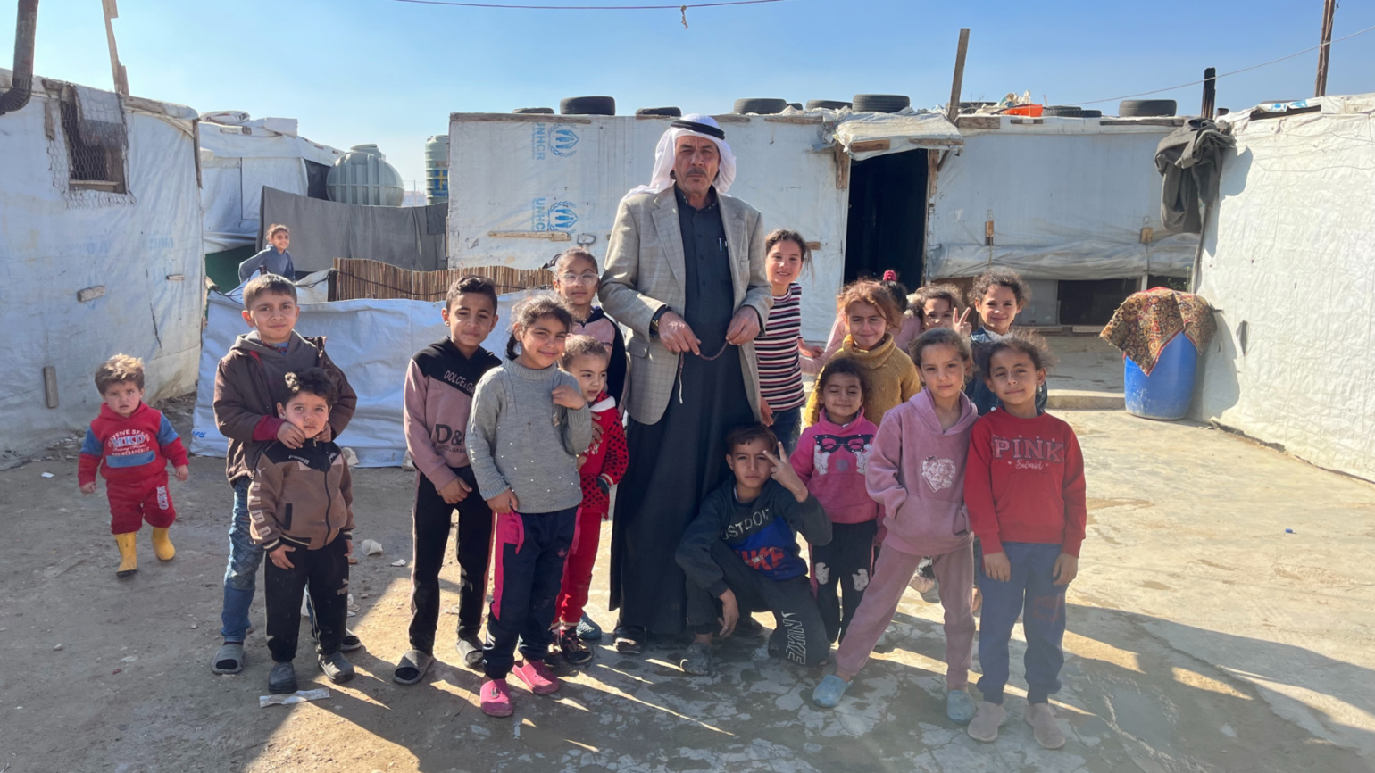 Mahmoud Ahmed Mohammed poses for a picture with Syrian children in a refugee camp in Saadnayel, eastern Lebanon on 18 December 2024 (Nader Durgham/MEE)