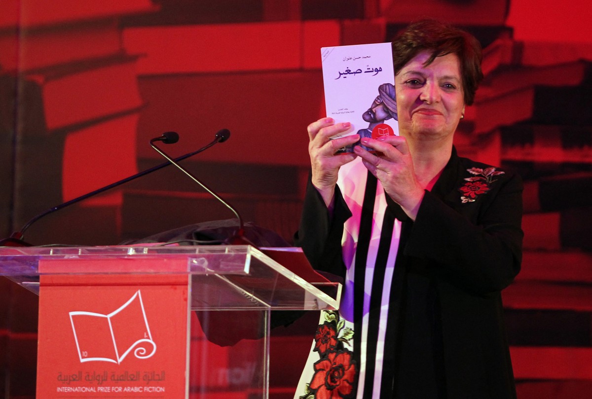 Palestinian novelist and chair of the judging committee Sahar Khalifeh poses for a photo with the winning book of the 2017 International Prize for Arabic Fiction by Saudi Arabian writer Mohammed Hasan Alwan in 2017 (AFP)