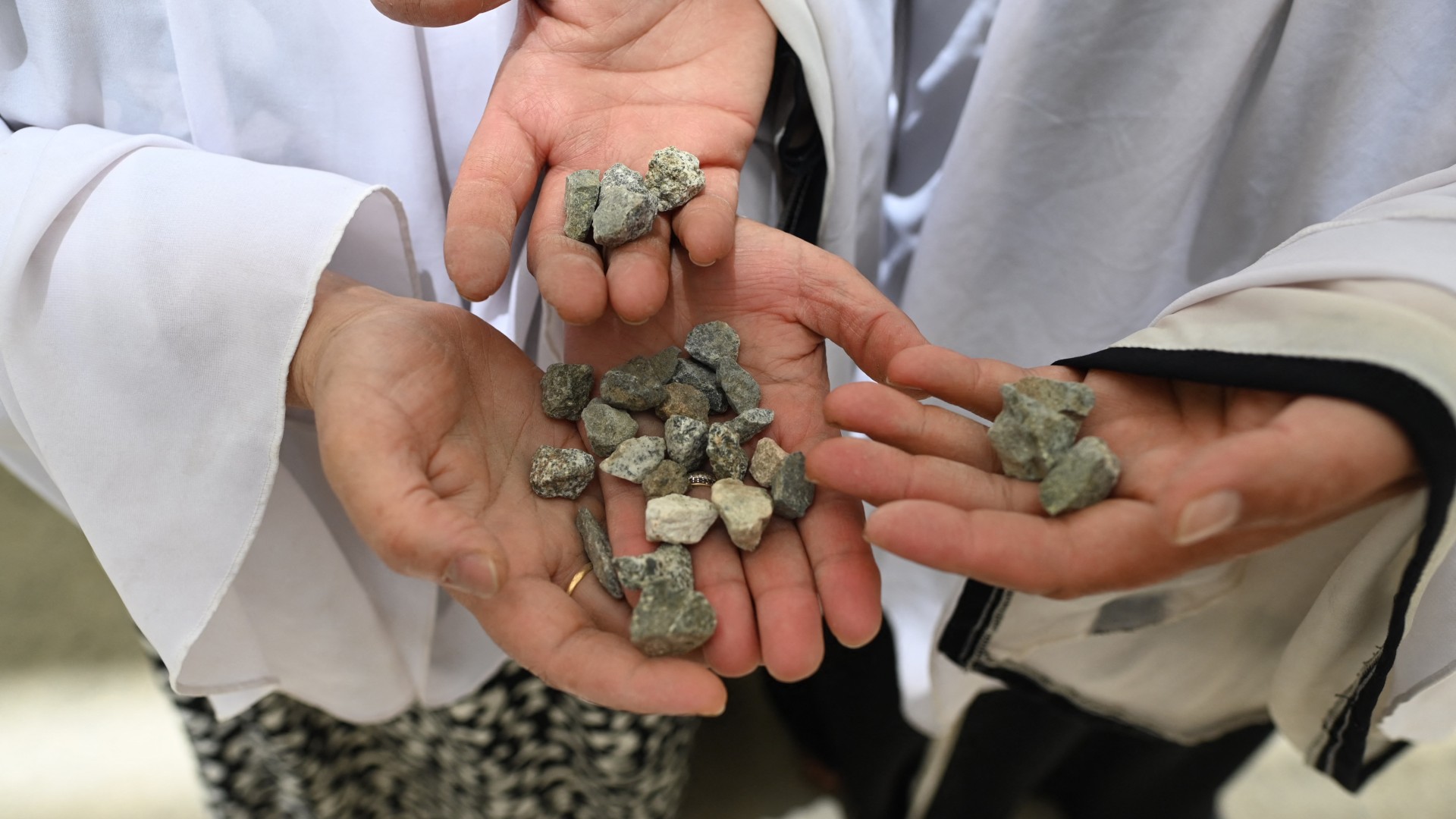 Muslim pilgrims hold stones as they prepare to perform the symbolic stoning of the devil ritual as part of the Hajj pilgrimage on 28 June 2023 (Sajjad Hussain/AFP)
