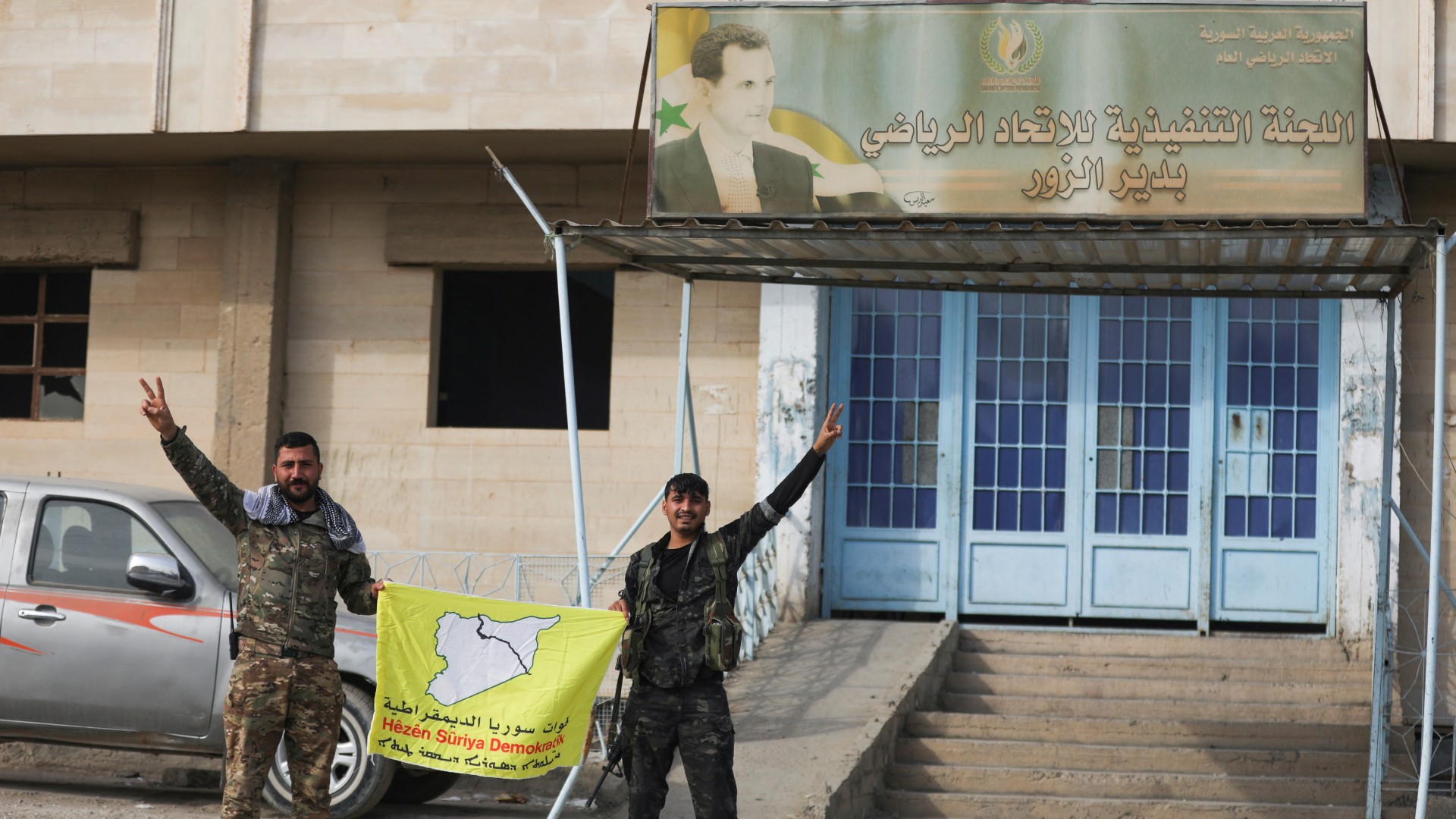 Members of the SDF hold a flag in Deir Ezzor on 7 December (Reuters/Orhan Qereman)