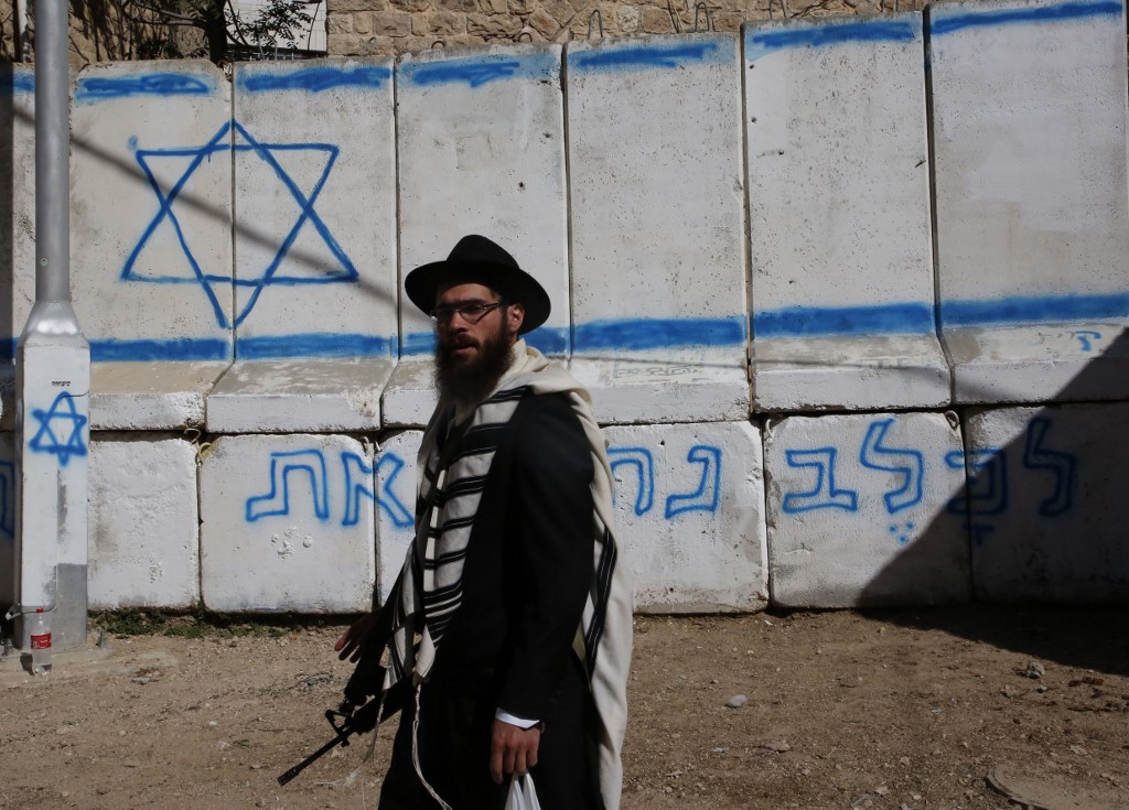 An armed Israeli settler stands near the Ibrahimi Mosque in Hebron in 2018 (AFP)