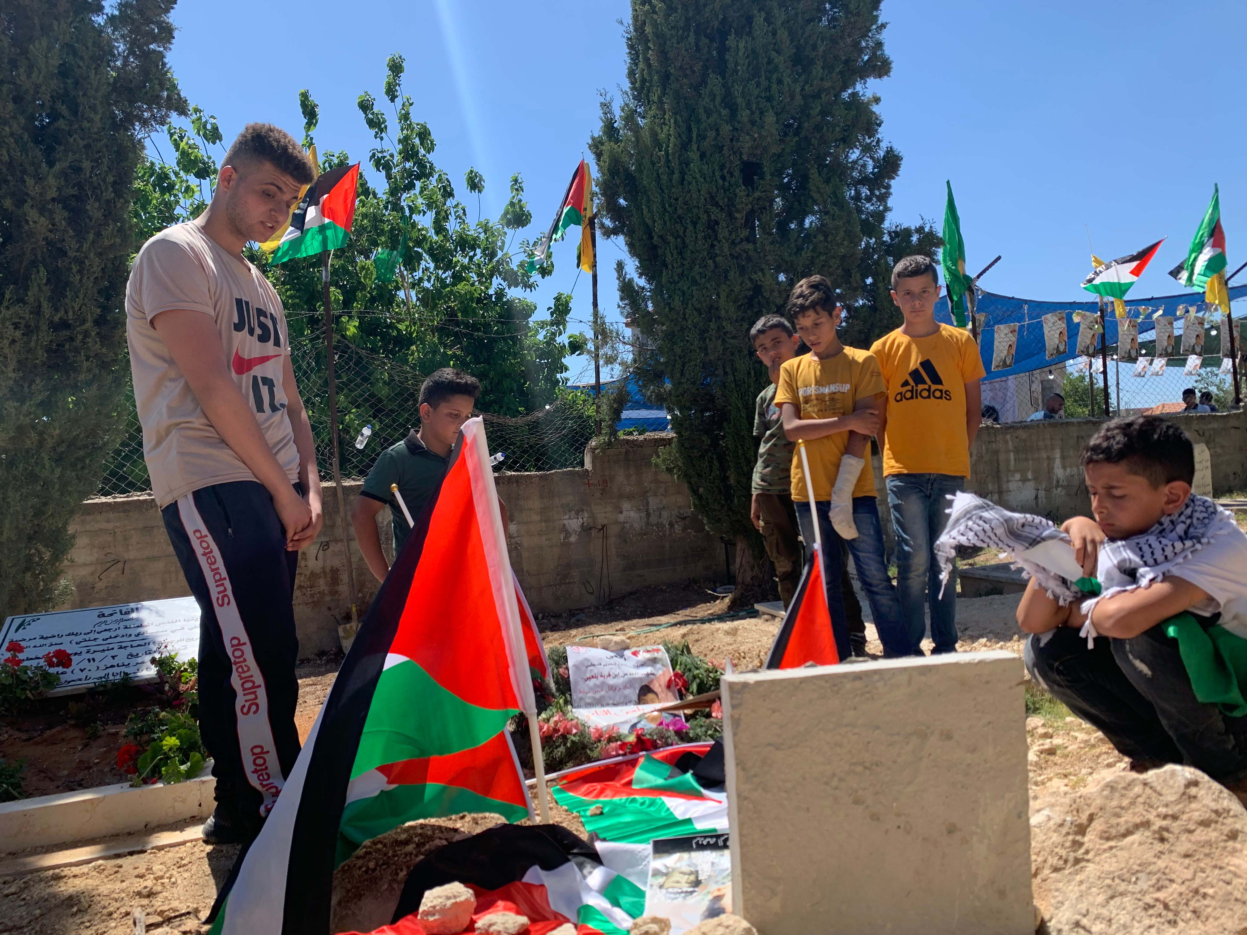 Islam Burnat's friends gather around his grave.