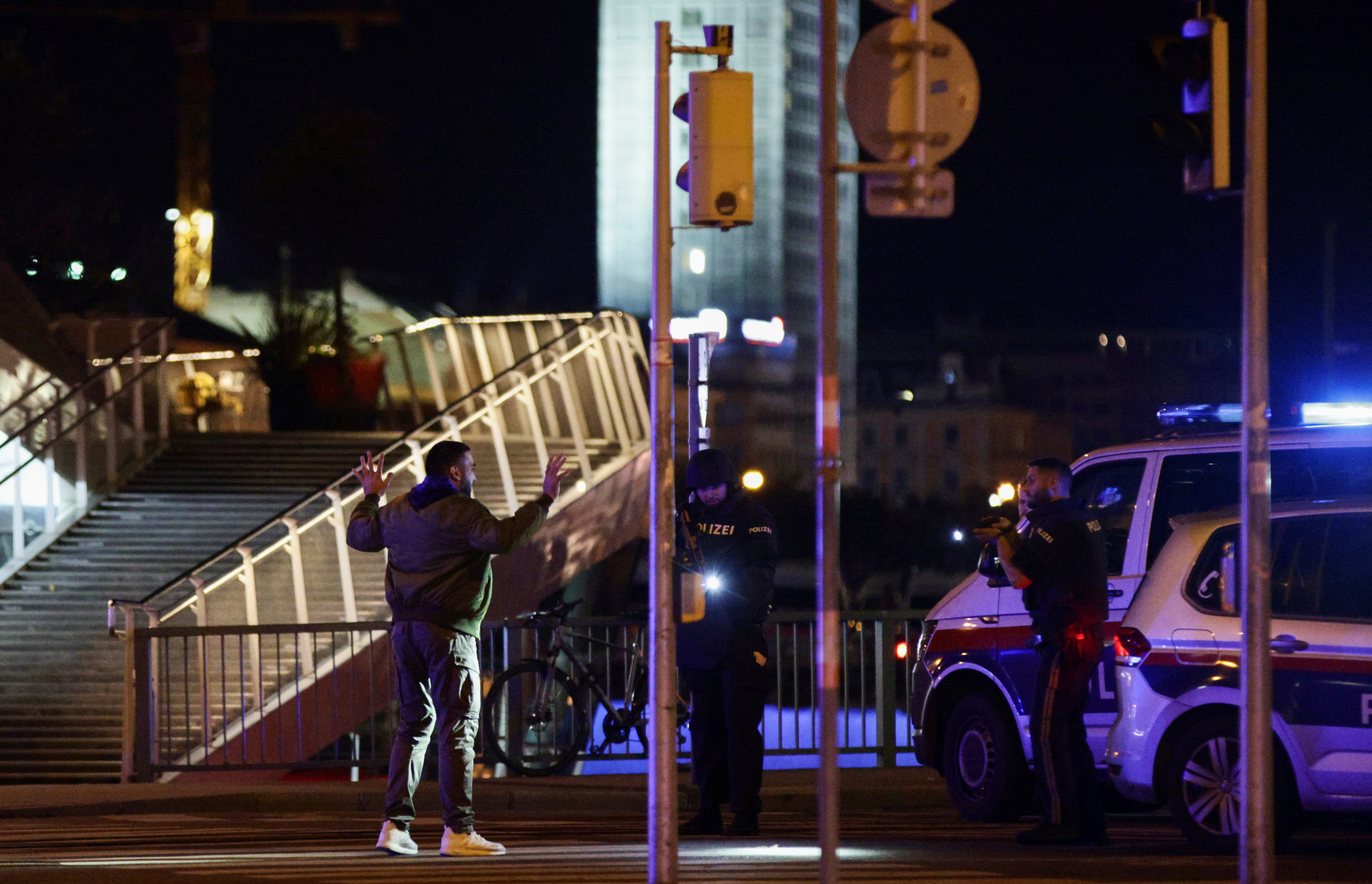 Police officers check a person on a street after exchanges of gunfire in Vienna, Austria.