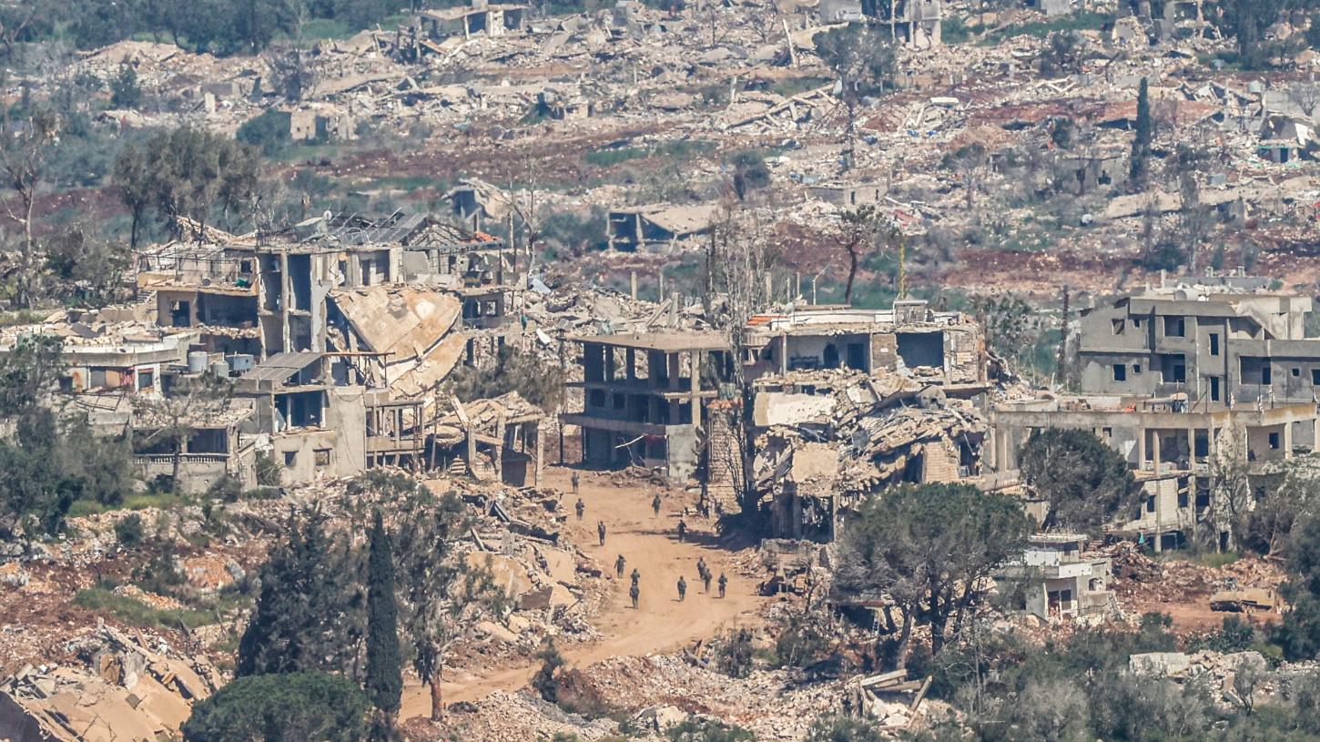 This photograph taken from northern Israel shows Israeli soldiers walking along the road between destroyed houses in southern Lebanon near the border with Israel, on 27 April 2026 (AFP)