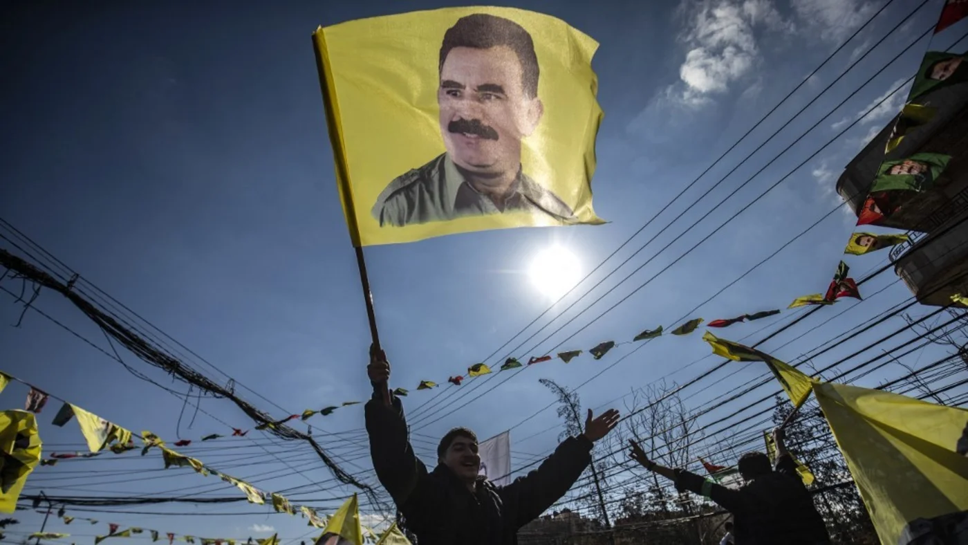 A protester waves a flag bearing a portrait of Abdullah Ocalan in February 2025 (AFP)