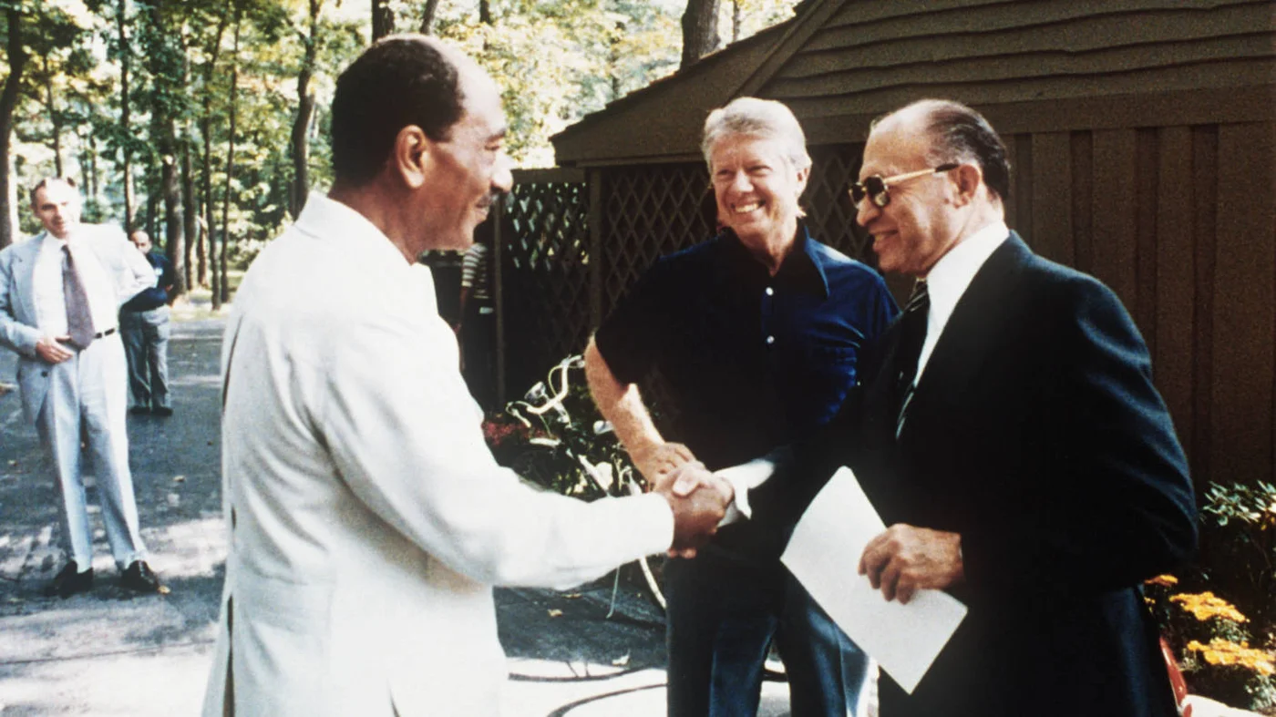 Egyptian President Anwar al-Sadat shakes hands with Israeli Premier Menachem Begin, as US President Jimmy Carter looks on, at Camp David, Maryland on 6 September 1978 (AFP)
