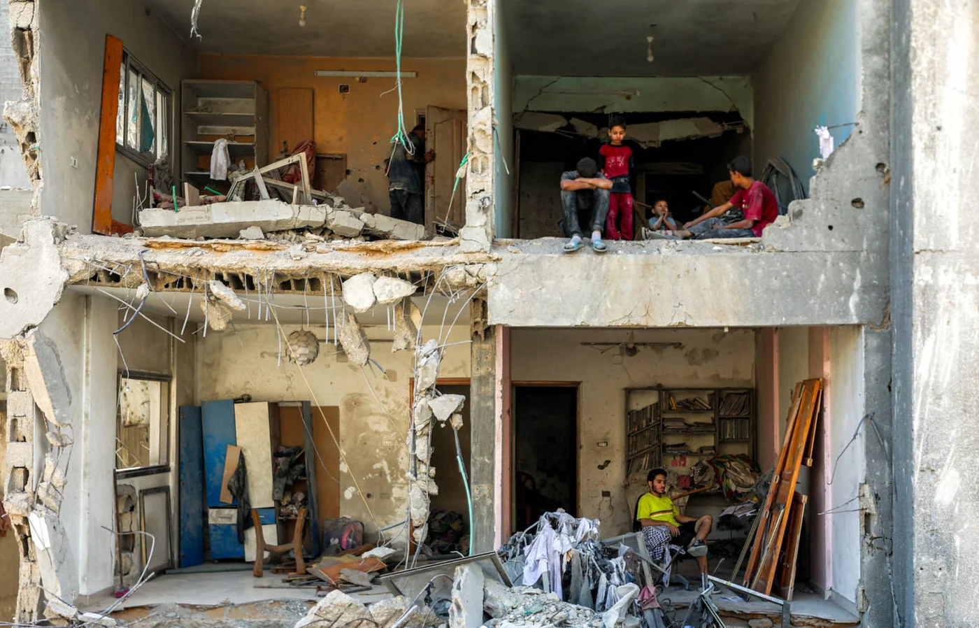 A man and children sit in exposed rooms in a heavily damaged building the Rimal neighbourhood, Gaza City on 15 September 2025 (AFP)