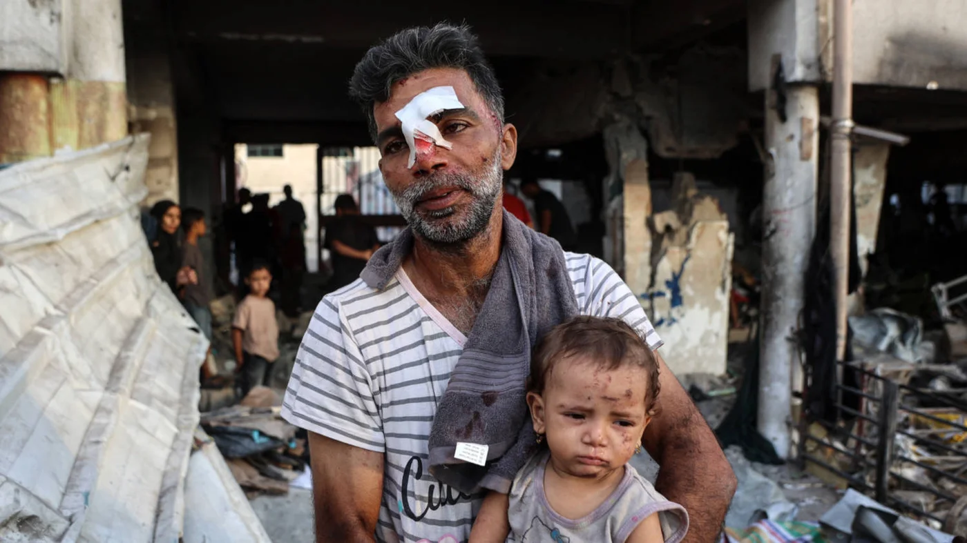 ​  An injured man carries a toddler after a school-turned-shelter was hit by an Israeli strike in Gaza City in September 2025 (AFP)  ​