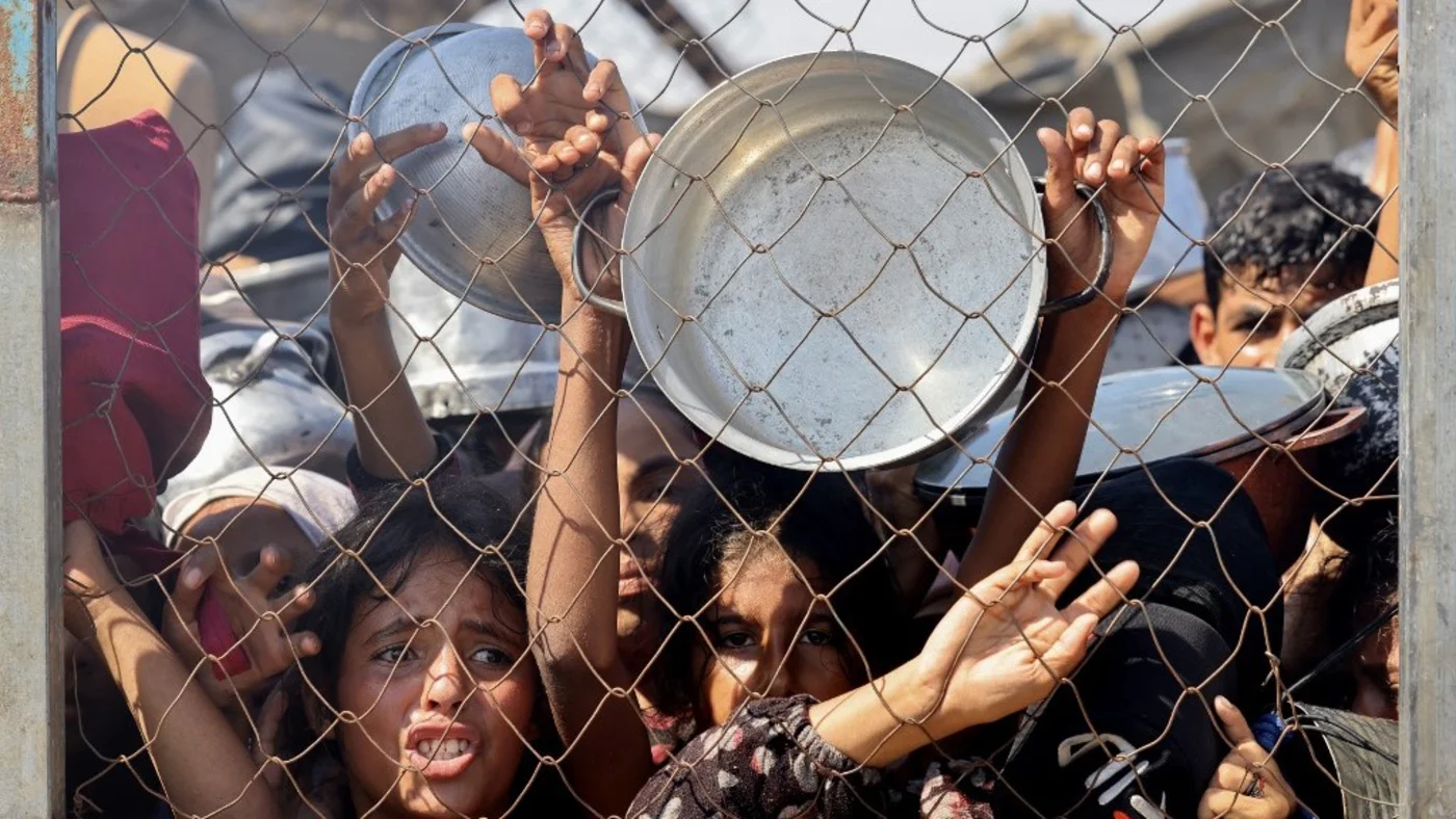 Palestinians, mostly children, push to receive a hot meal at a charity kitchen in the Mawasi area of Khan Younis in the southern Gaza Strip, on 22 July 2025 (AFP)
